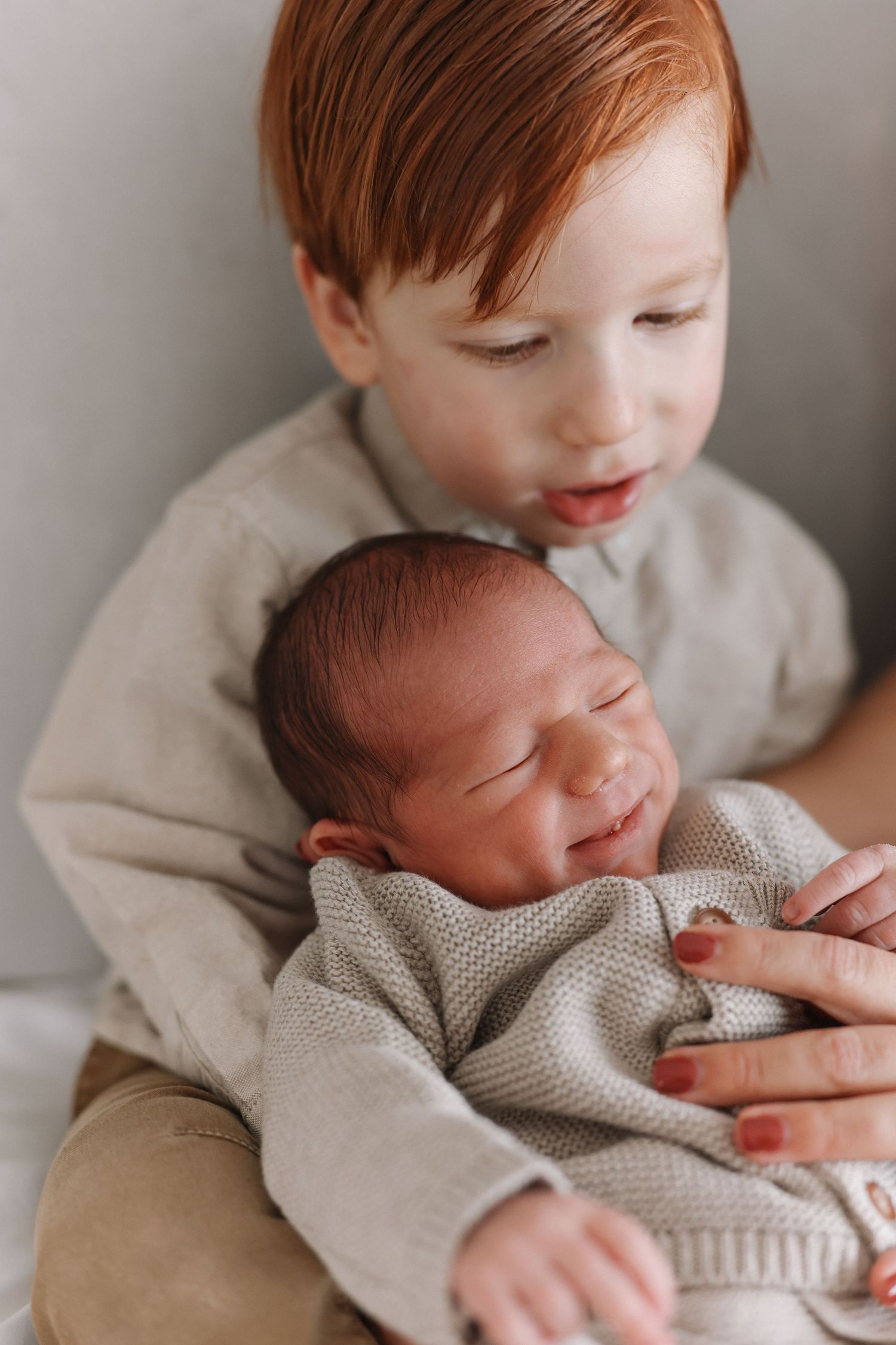 Four connected images showing a newborn swaddled in gray knit blanket being cradled by gentle hands.