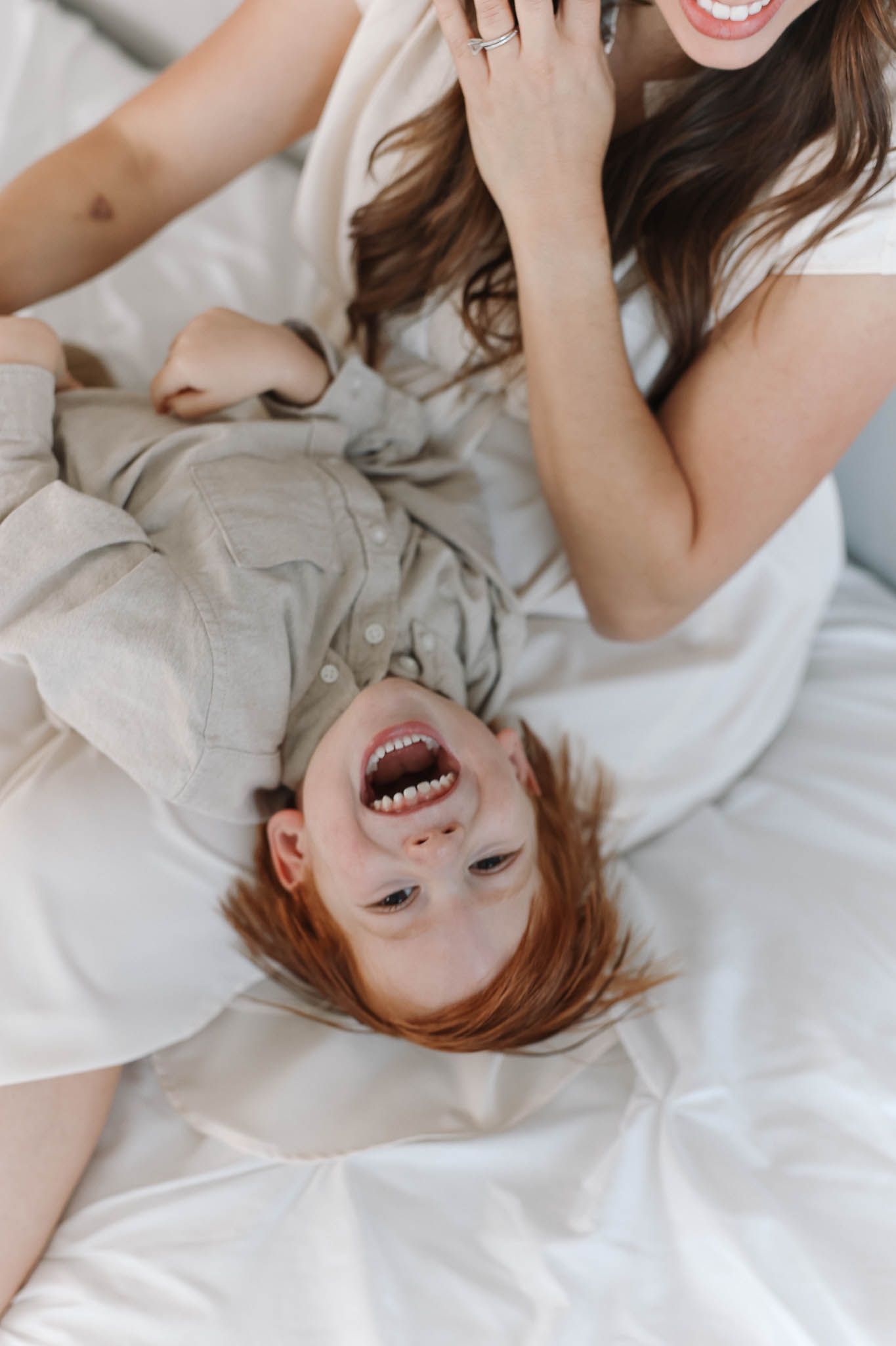 A joyful candid series showing someone lying with flowing hair on white bedding while laughing and smiling.