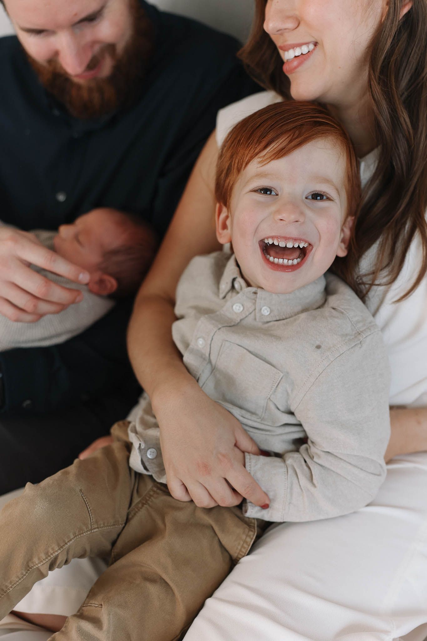 A joyful family moment captured in an intimate indoor portrait showing genuine laughter and embraces.
