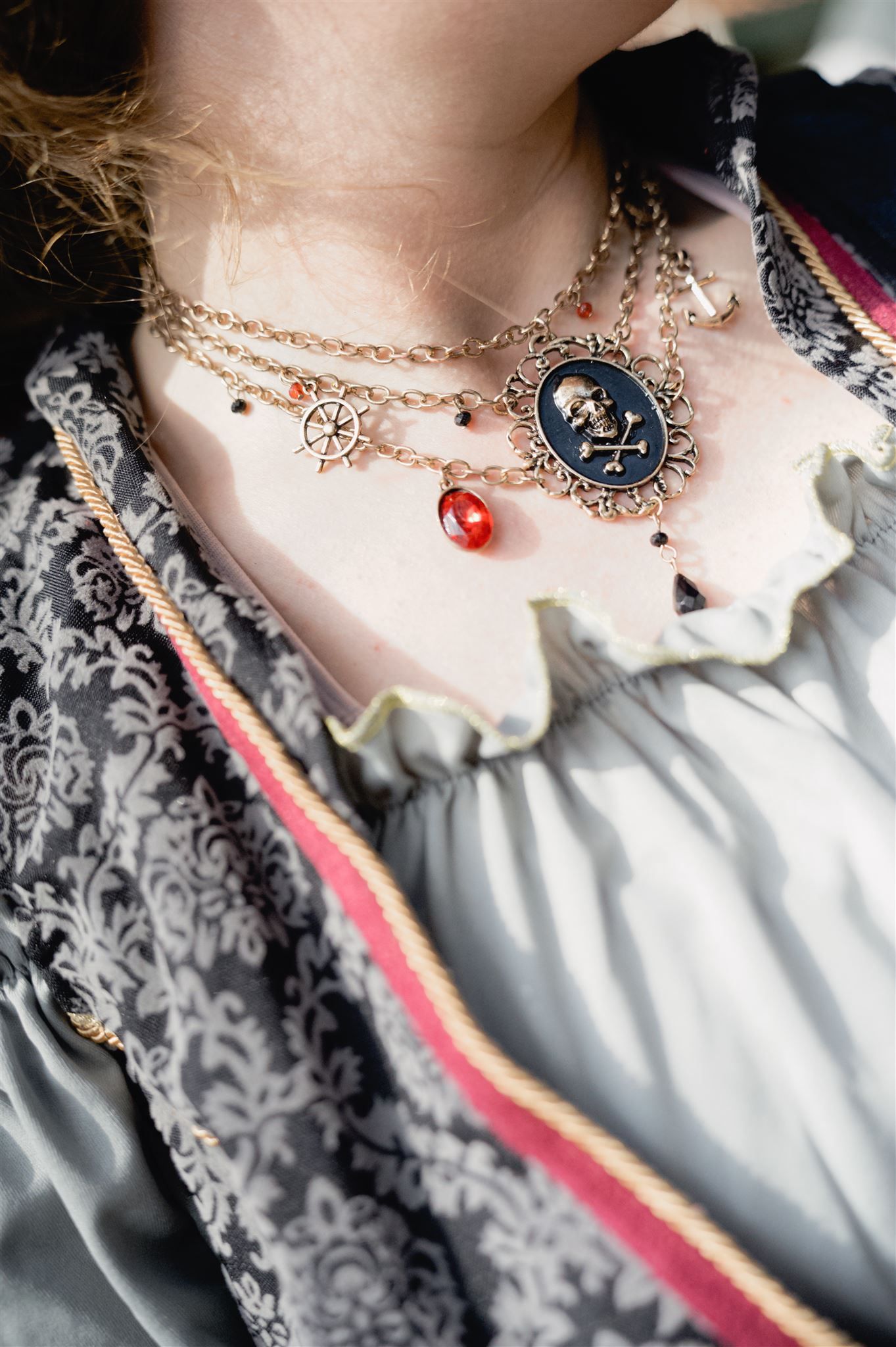 Vintage-style ornate necklace with pendant and red gem detail shown against Victorian-inspired lace dress collar.