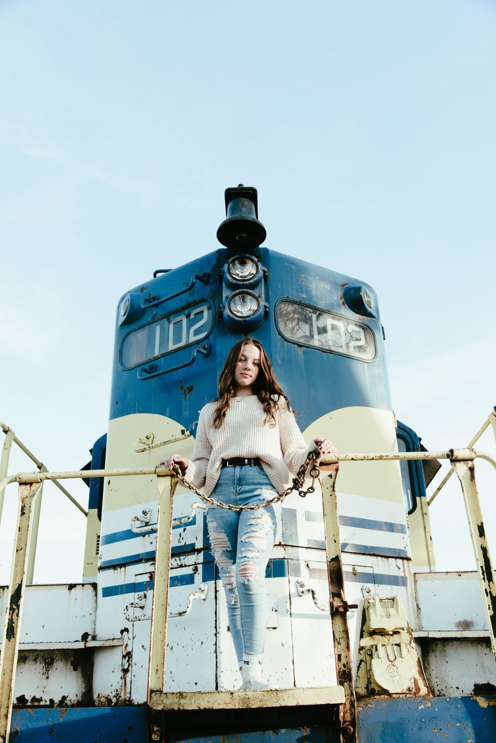 Fashion portrait on vintage blue train with distressed denim and white sweater.