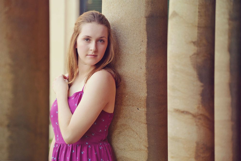 Portrait against classical stone columns in soft lighting.