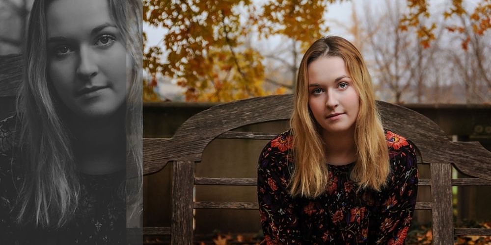 Portrait against autumn trees and wooden bench backdrop.