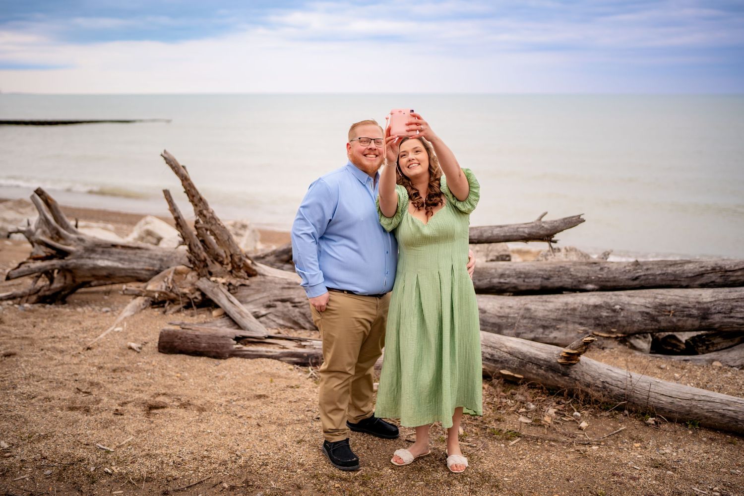 A couple poses together on a beach with driftwood near Jekyll Island during golden hour.