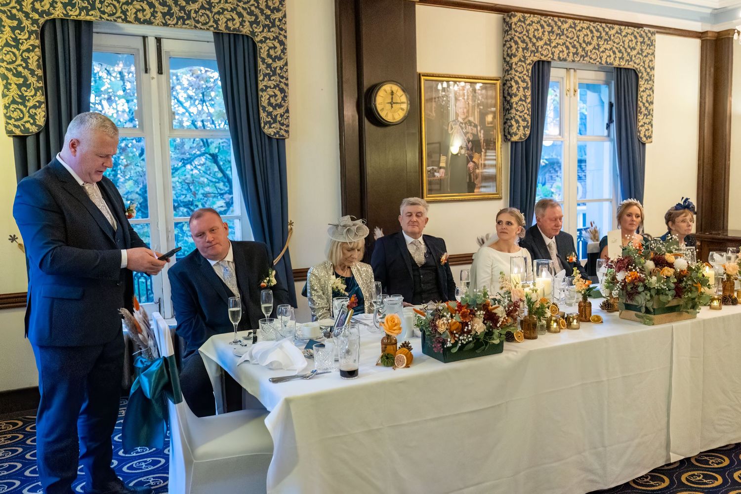 best man standing by the top table gives his speech as the wedding party listen. Stuart Morris Photography at the Athenaeum liverpool.