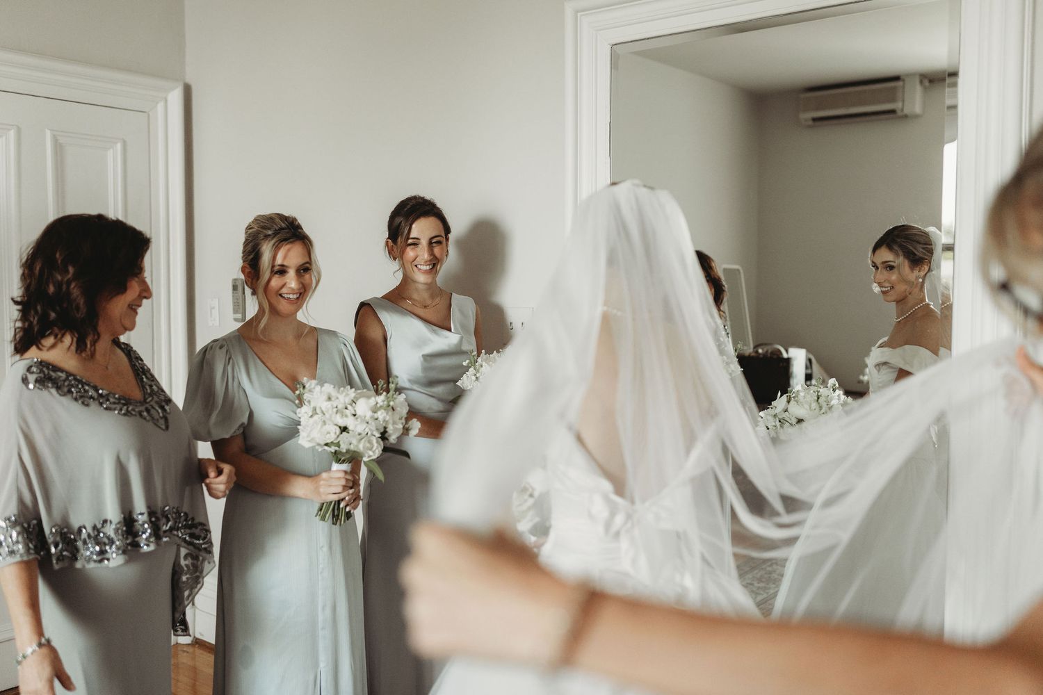 Elegant group getting ready together in a white bridal suite on wedding day morning.