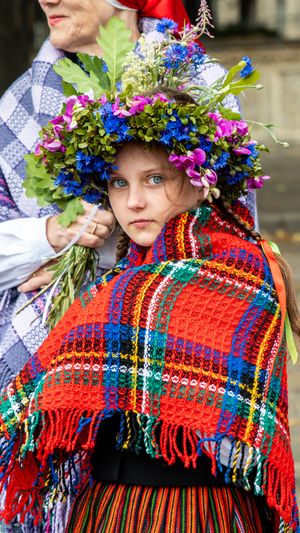 Traditional festival attire with floral crown and colorful plaid shawl.