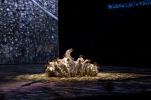 Dramatic stage performance with dancers in spotlight creating artistic formation.