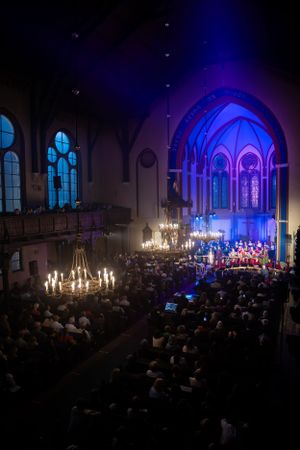 Gothic church interior with blue lighting during evening concert performance.