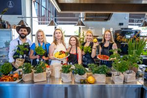 Group display fresh produce and plants at cooking demonstration station.