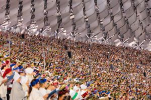 Massive crowd under geometric canopy structure at large outdoor event.