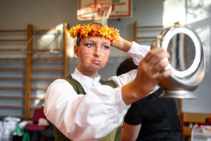 Traditional folk costume with flower crown reflected in hand mirror.