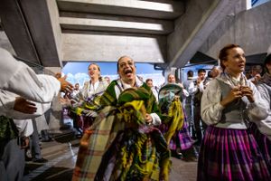 Traditional folk dancers in colorful costumes performing at an indoor venue.
