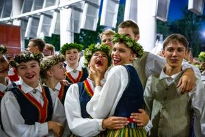 Group wearing traditional folk costumes and flower wreaths celebrating at a festival.