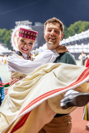 Dancers in traditional Baltic folk costumes performing at an outdoor festival.