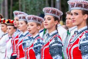 Row of performers in traditional Estonian folk costumes and ornate headdresses.