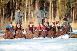 Group wearing historical costumes posing together in snowy winter setting.