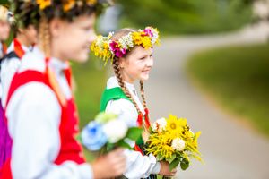Performer wearing traditional folk costume and flower crown at cultural celebration.
