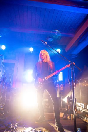 Bass player performs on stage with dramatic blue lighting and fog effects.