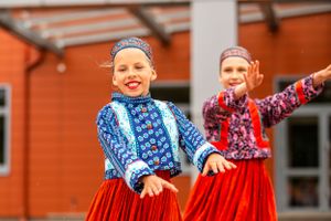 Traditional folk dancers in blue and red costumes performing energetic dance routine.