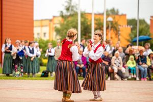 Traditional folk dancers in striped skirts performing at outdoor cultural event.