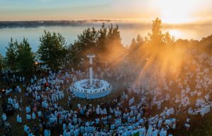 Aerial view of sunset gathering with crowd surrounding circular formation.