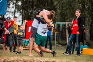 Athletes compete in an outdoor sporting event with spectators watching from the sidelines.