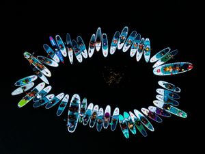 Aerial view of paddleboards arranged in a circular pattern creating a unique design on dark water.