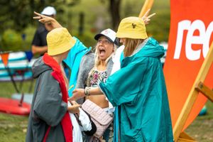 Group wearing colorful summer gear and hats gathered around a red outdoor banner.