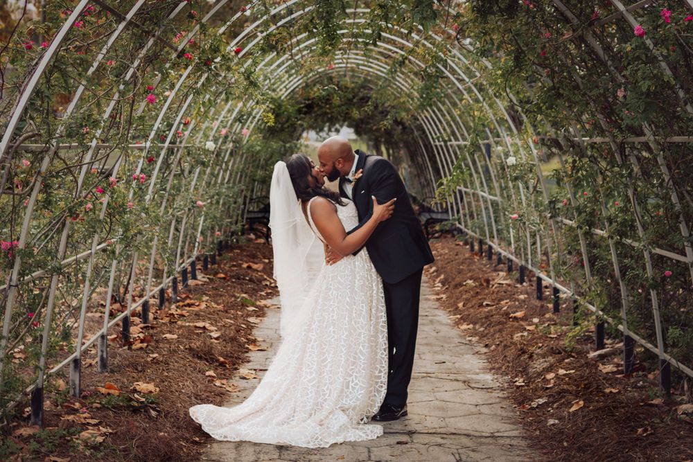 A romantic moment captured under a flower-covered garden arbor walkway in Springfield historic district in Jacksonville, Florida.