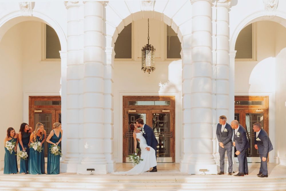 Wedding party poses under white archways of an elegant building at Wilmington Plantation in Savannah, Georgia .