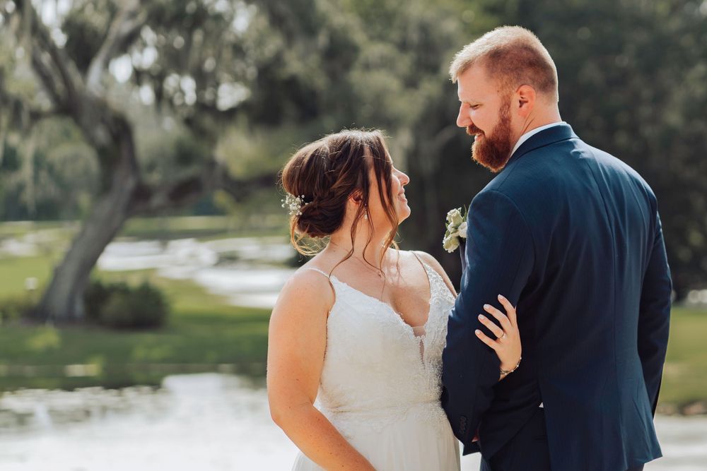 A couple shares an intimate moment outdoors near a pond on their wedding day in Ocala, Florida.