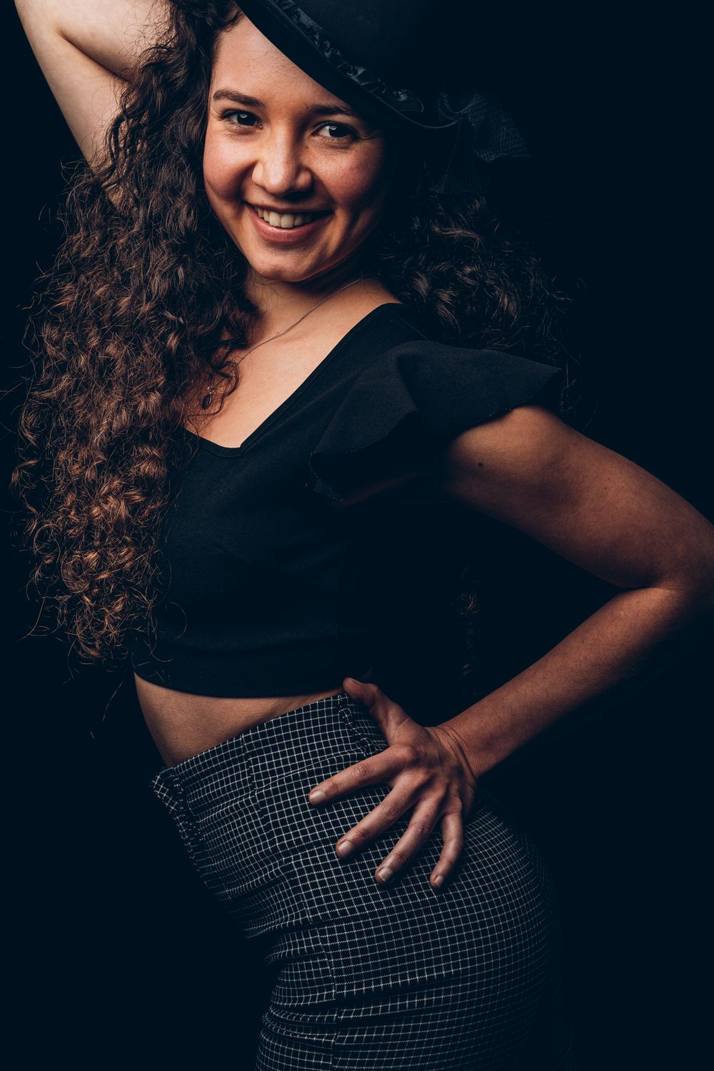 A creative portrait series showing dynamic poses in black attire against a dark backdrop with dramatic lighting.