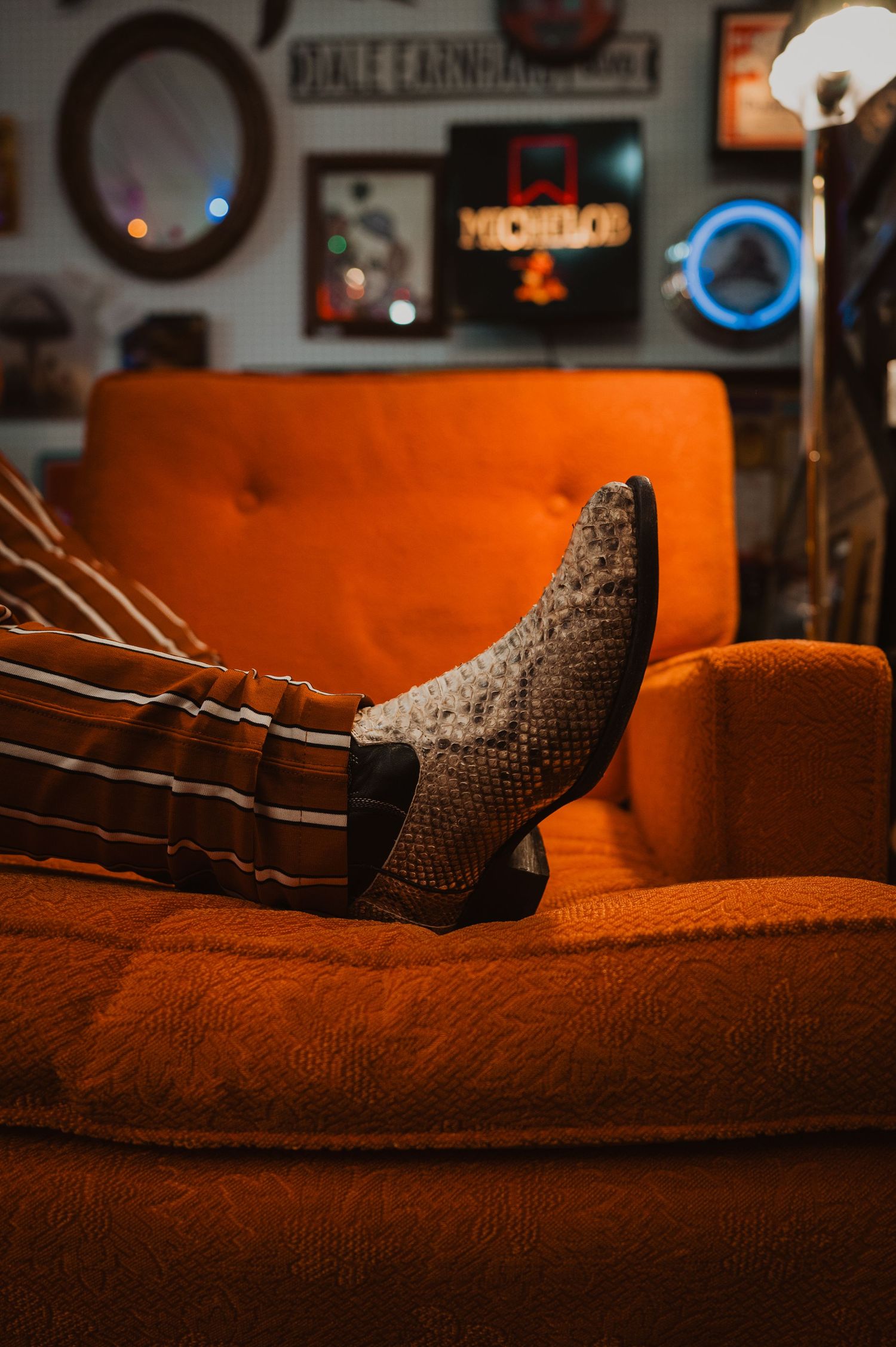 A silver or metallic snake-like mesh object coiled on an orange fabric surface in dramatic low lighting.