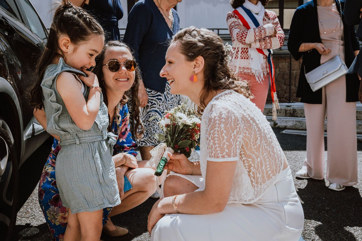 Wedding guests mingle and celebrate outdoors on a sunny summer day.