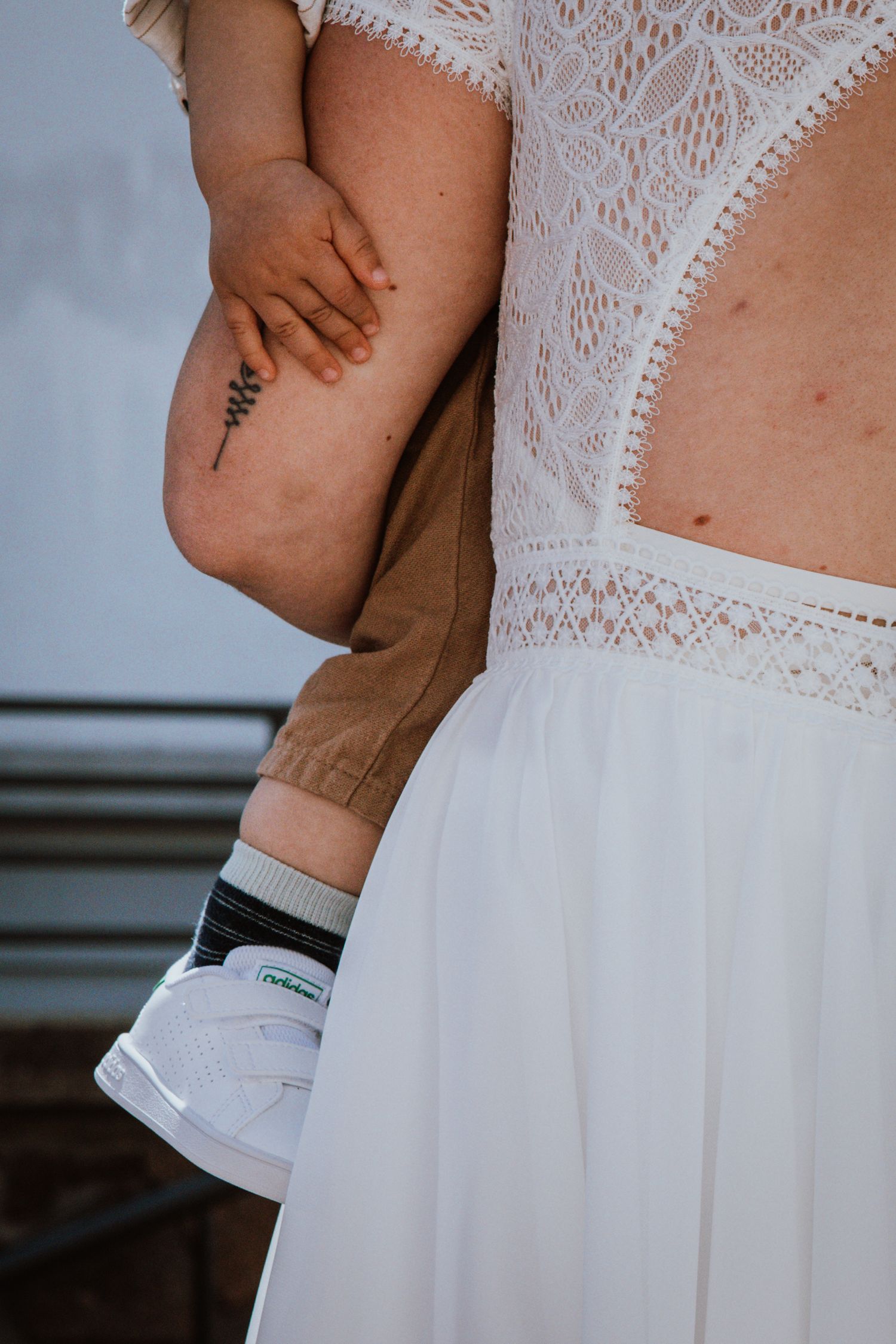 Close-up details of a white lace wedding dress showing delicate fabric patterns and texture.