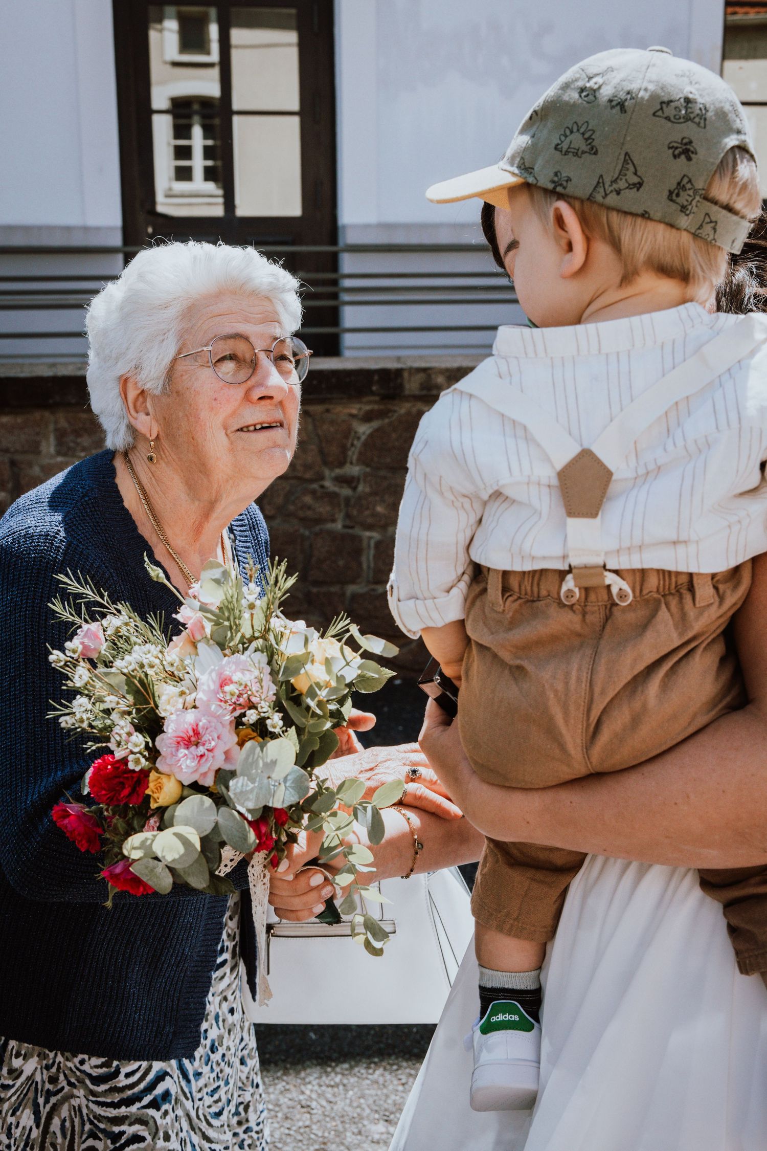 A heartwarming sequence of a young child embracing an elderly person while holding a colorful floral bouquet.