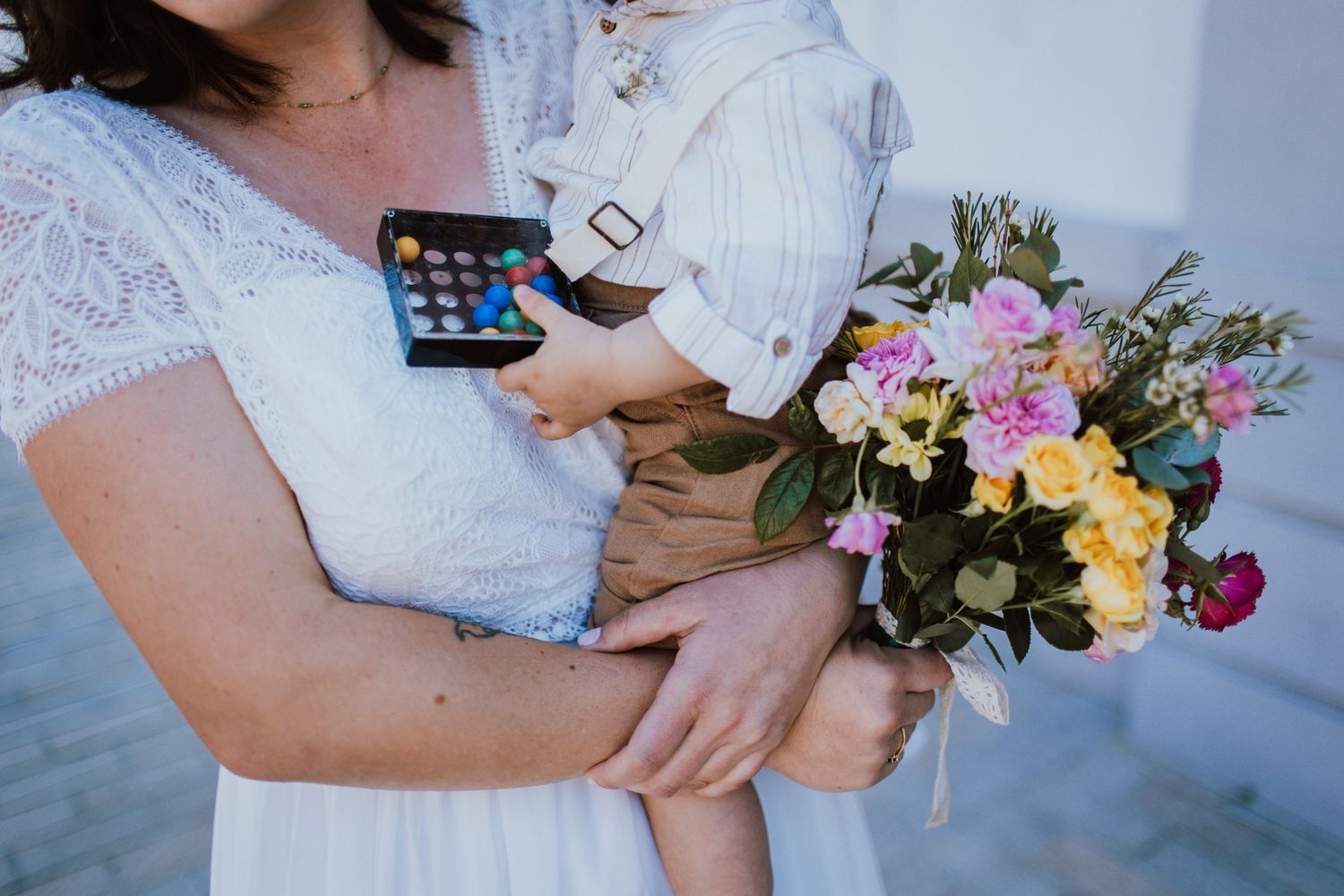 Someone holding a smartphone embraces another while holding a colorful bouquet of mixed floral blooms.