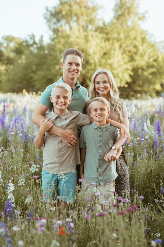 A family poses together in a field of vibrant purple wildflowers during golden hour.