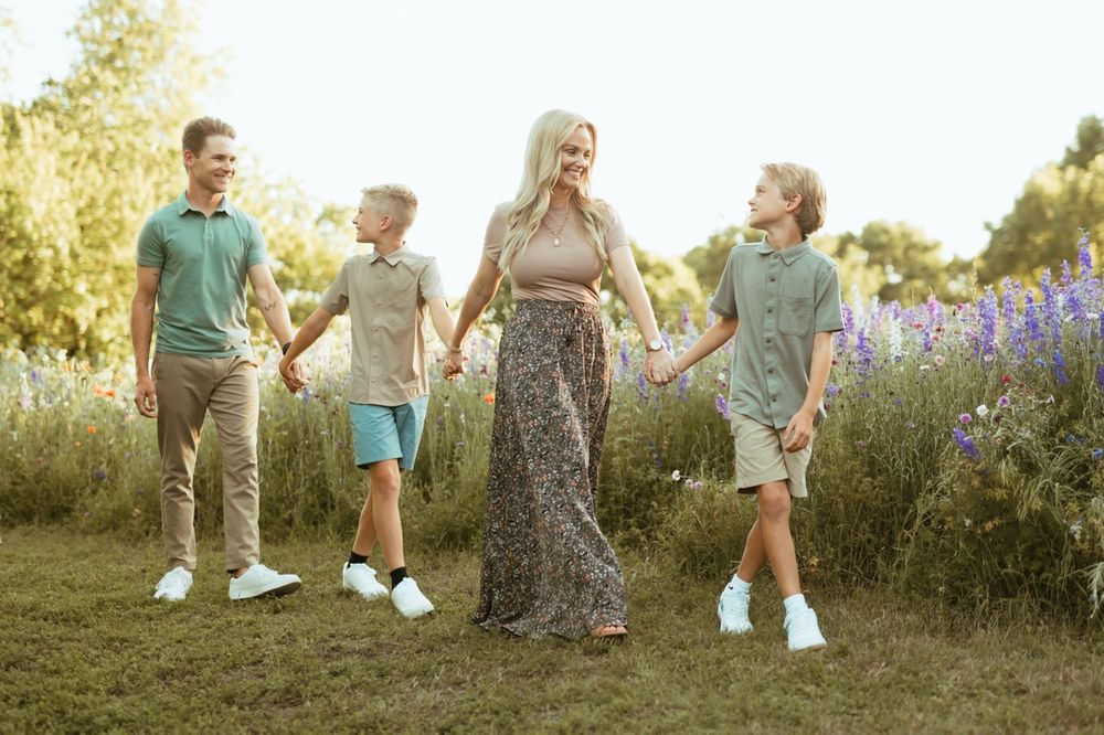 A family walking together through a blooming wildflower meadow on a sunny summer evening.