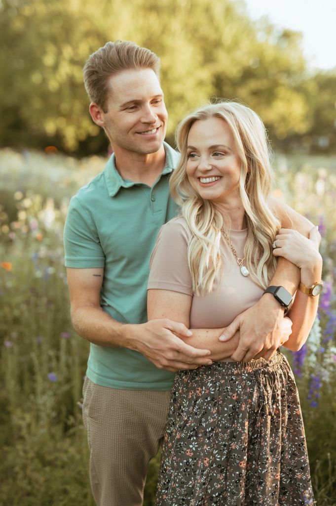 A romantic couple in a field share candid moments while embracing during their photoshoot at golden hour.