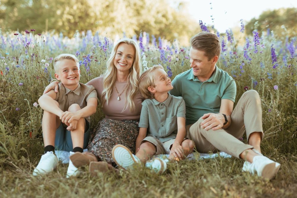 Family enjoying a playful moment together while sitting in a wildflower meadow at sunset.