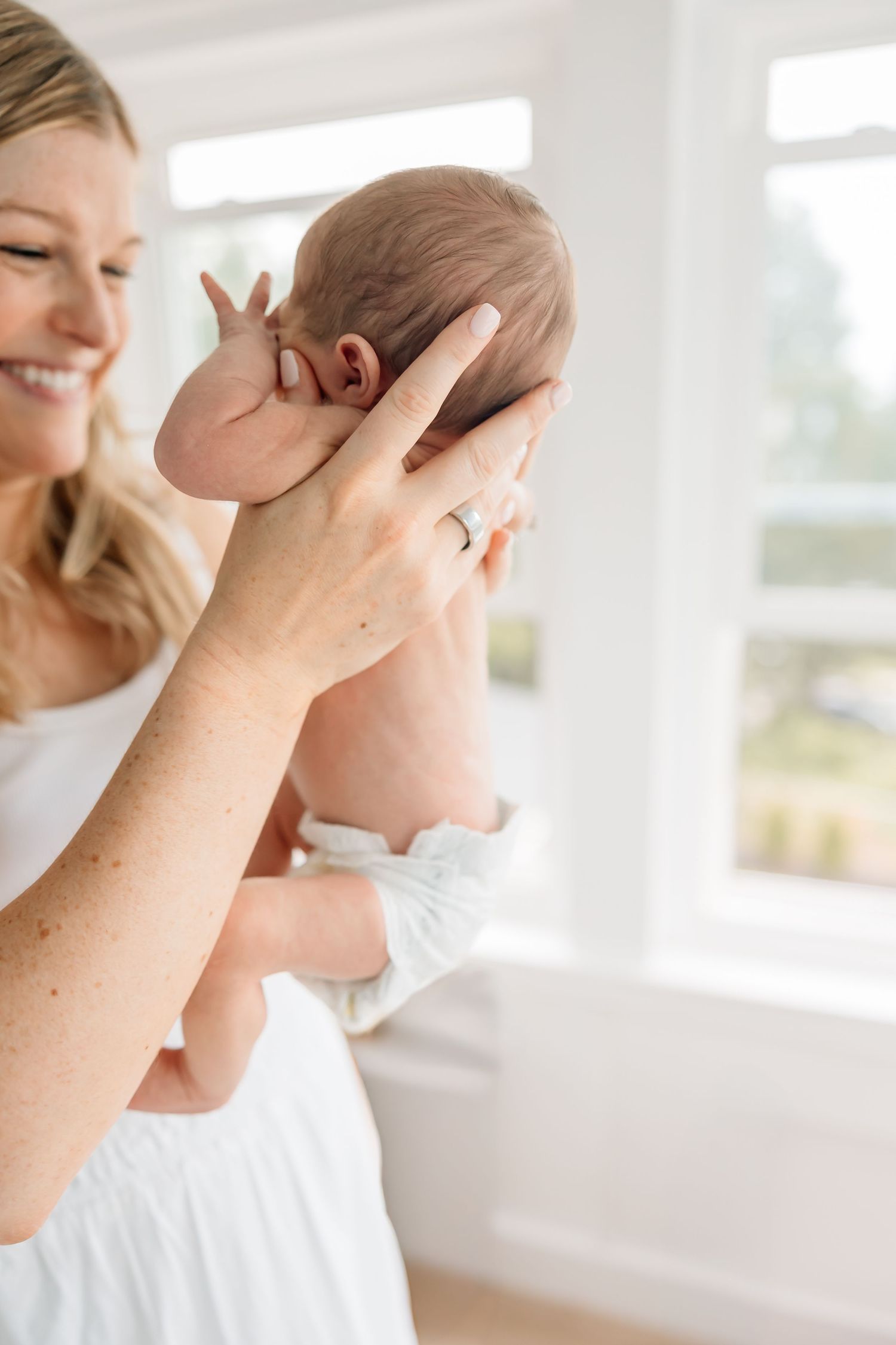 Gentle hand reaches to soothe crying baby in a bright sunlit room.