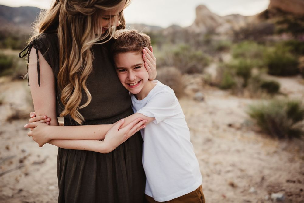 A tender embrace captured in a desert landscape with rock formations and desert brush in the background.