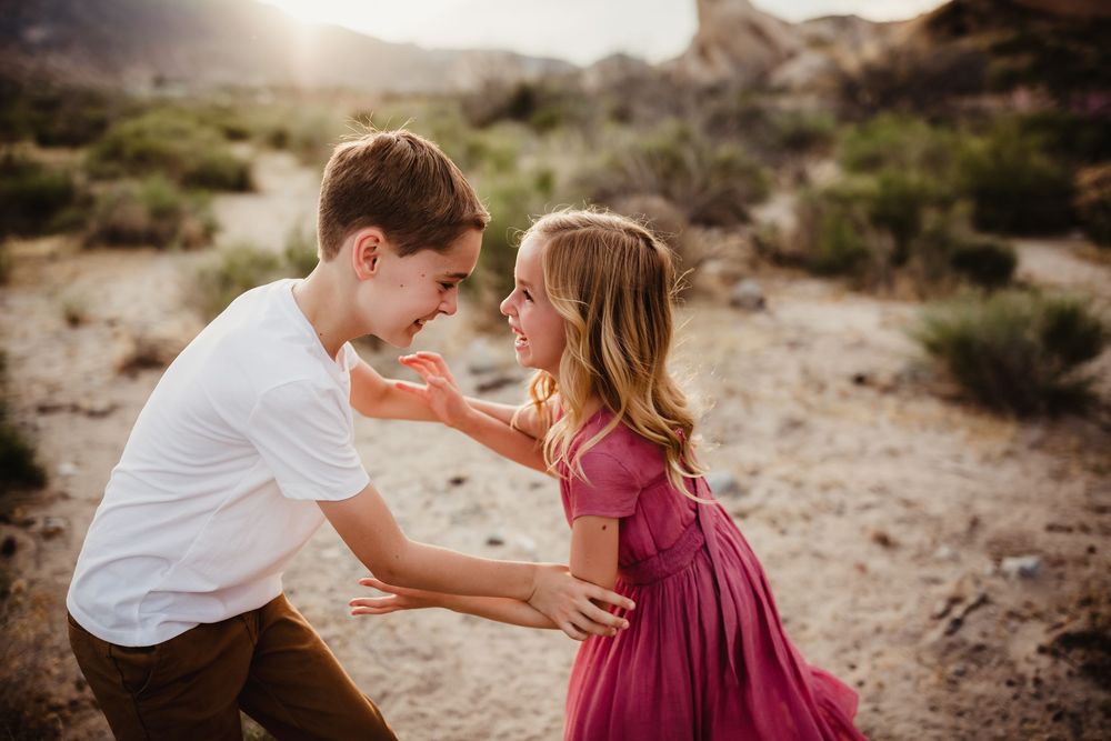 Family shares tender moments together in a sun-drenched desert setting with natural brush and rocks.