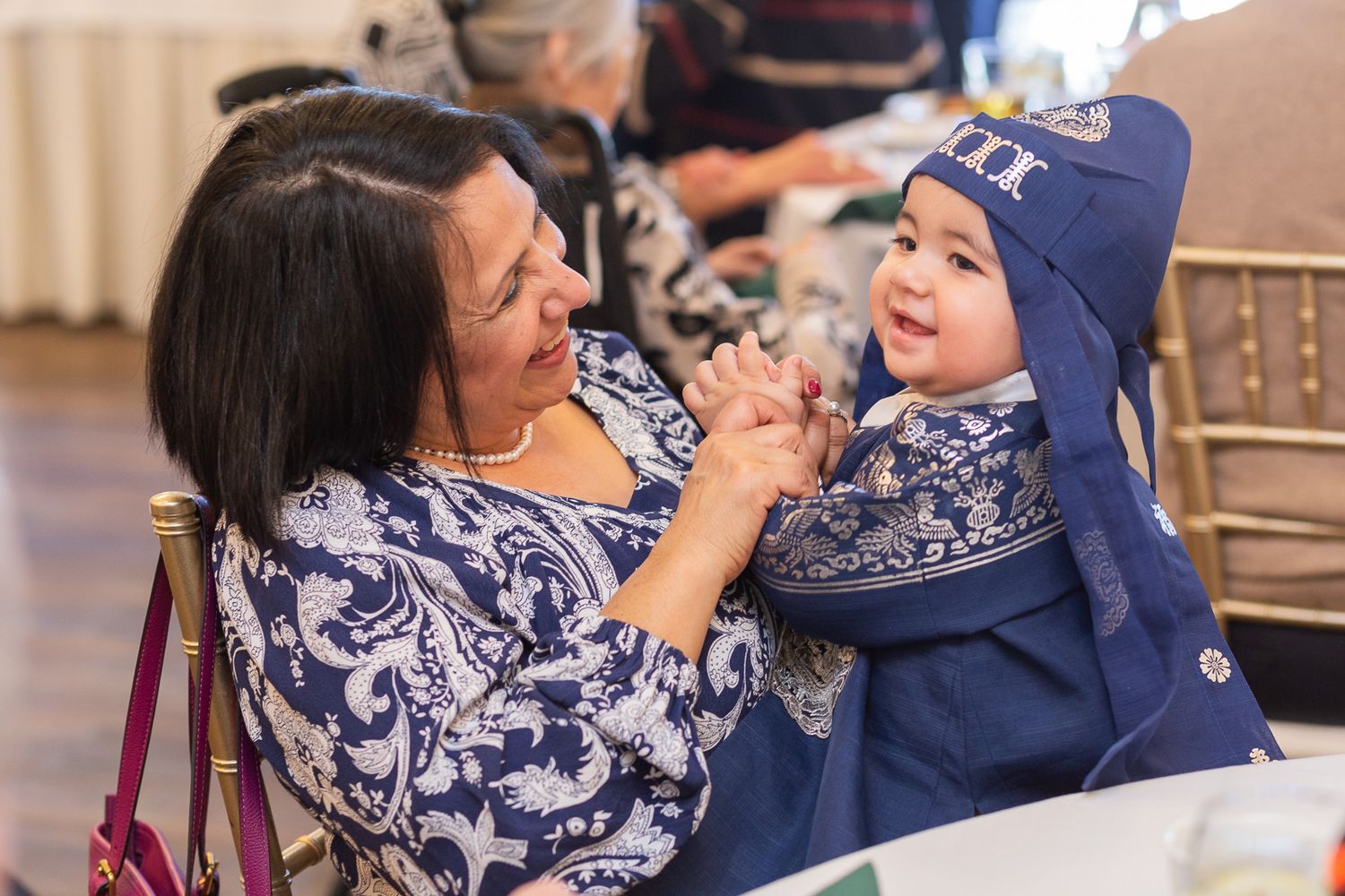 Two people in matching navy blue and white floral patterns share a joyful moment together indoors.
