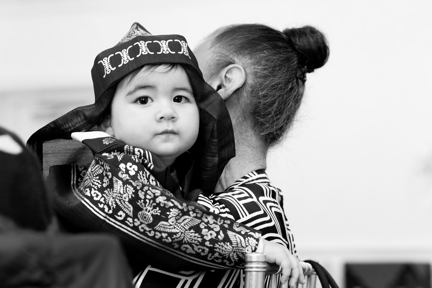A child wearing traditional dress and decorative hat poses during a cultural celebration.