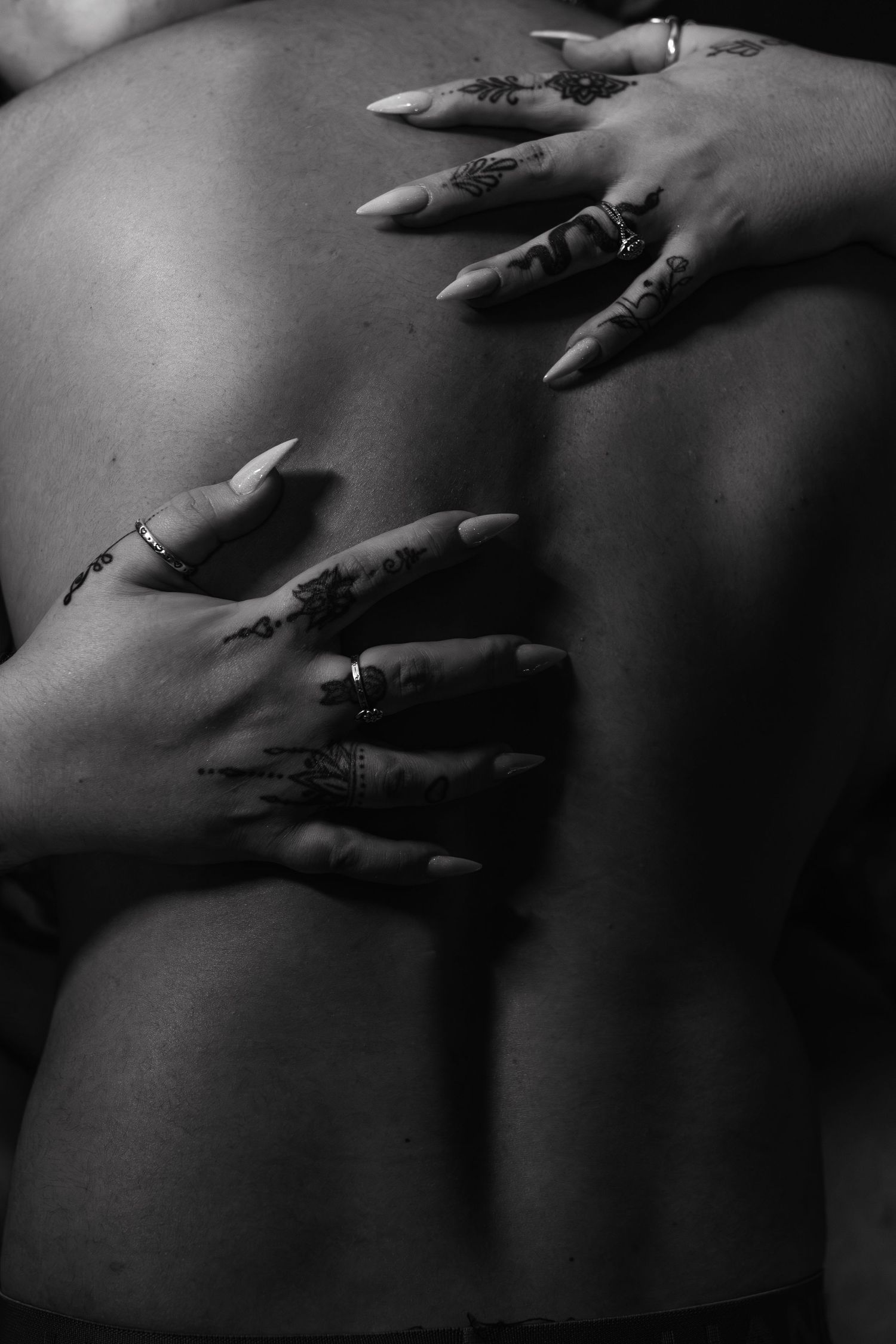 An artistic black and white Fort Worth boudoir photo captured by Lock and Key Photography of a woman's hands on a man's back.