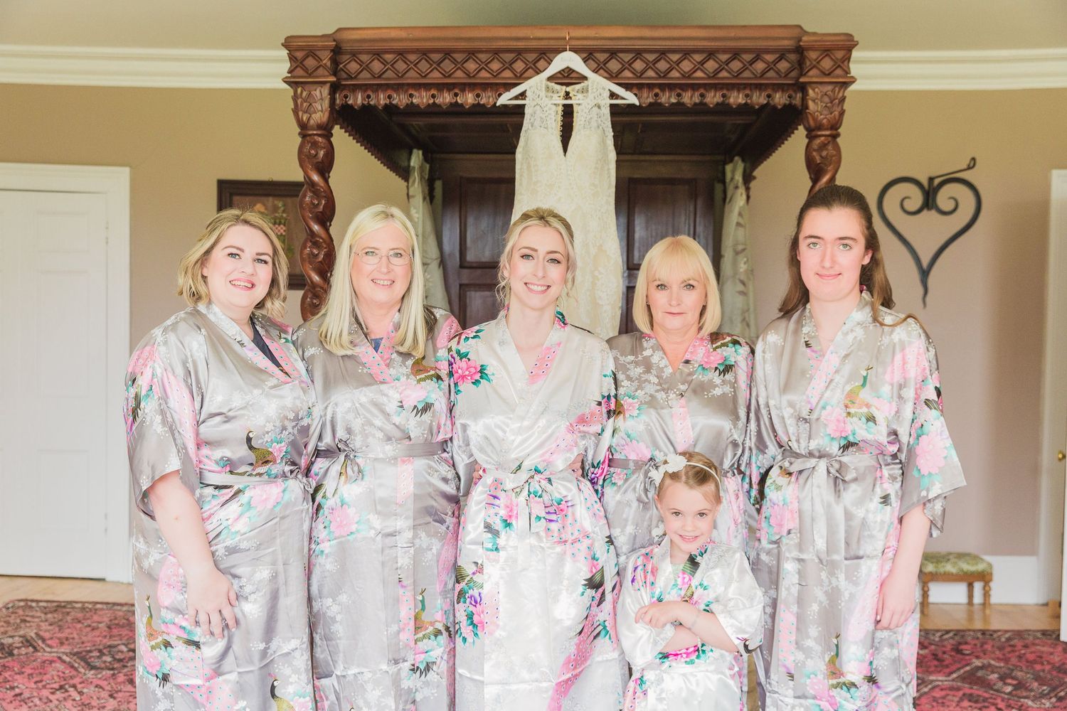 A bridal party group wearing matching floral robes pose together in an elegant room with ornate furniture at Homme House Hayley Elizabeth