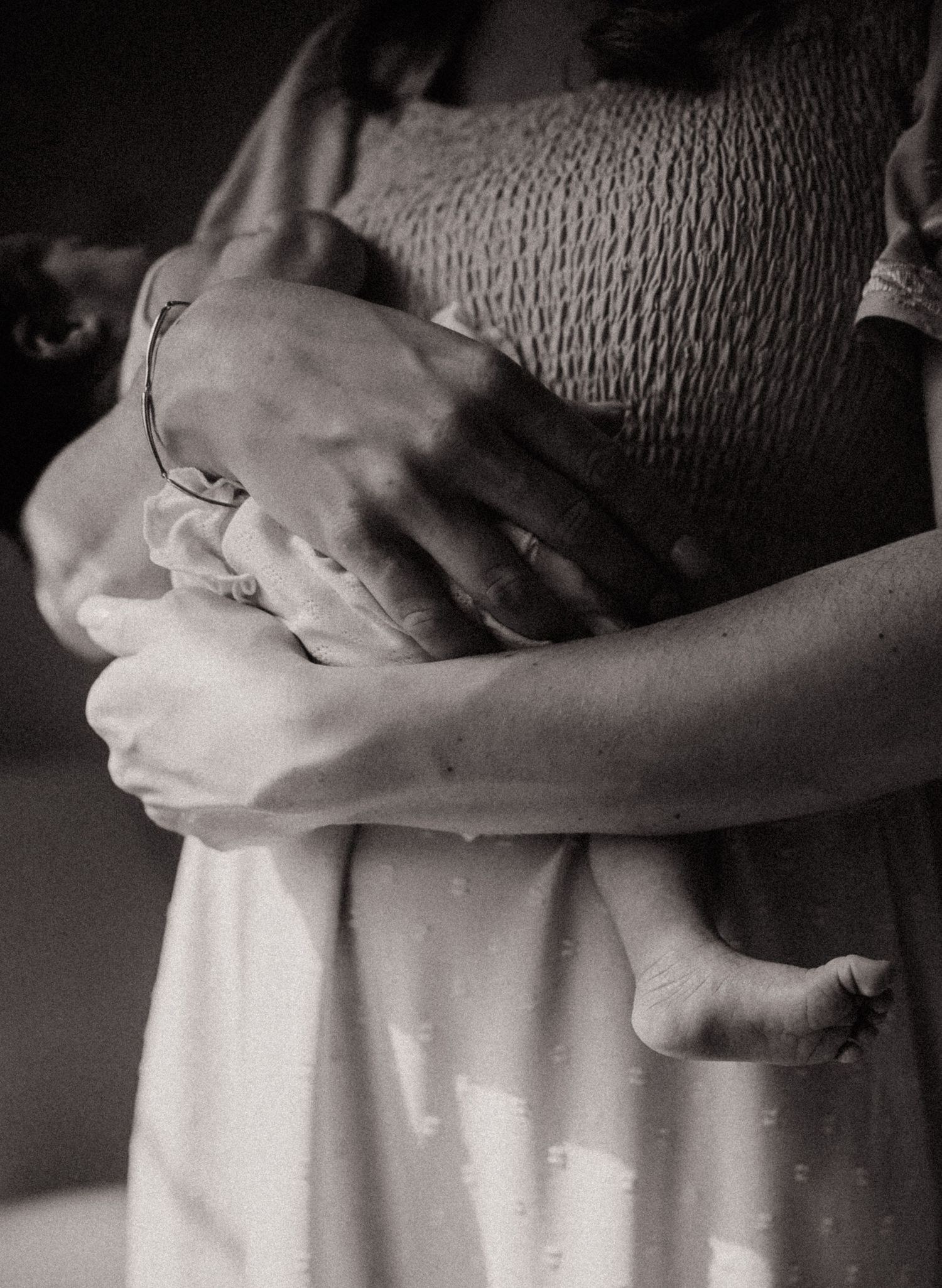 Black and white photo series showing hands tenderly cradling a growing pregnant belly in a progression of images.